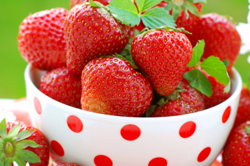 ein rotgepunktetes weißes Schälchen mti Erdbeeren